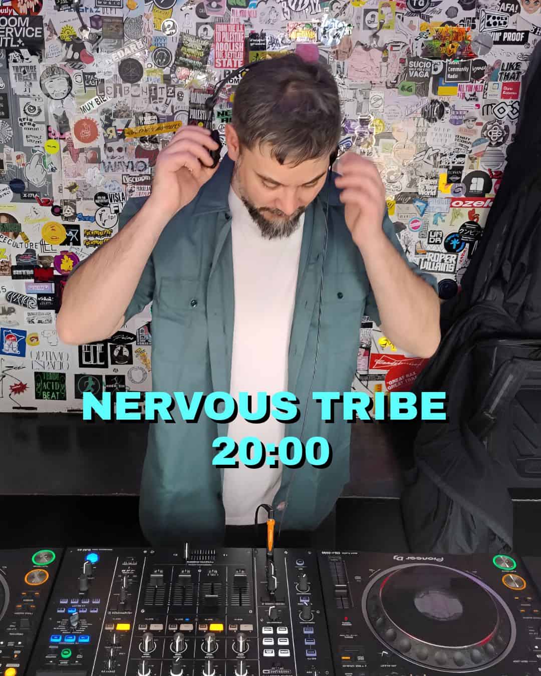 Nervous Tribe DJ performing live in a trendy club environment, surrounded by graffiti-style wall art.